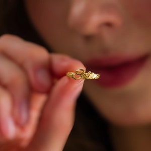 Könnte beinhalten: Ein goldfarbener Metallring mit einem Namensschild in Schreibschrift, auf dem Selene steht. Der Ring hat eine dünne, polierte Ringschiene und wird hochgehalten, um die detaillierte Beschriftung des Namens auf der Vorderseite zu zeigen.