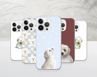 Puede incluir: Varias fundas para teléfono con perros blancos. Los diseños incluyen un perro con un girasol, un perro mirando las estrellas, un retrato de perro y un patrón de cuadros con caras de perro. Las fundas son de varios colores.