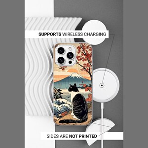 K&ouml;nnte beinhalten: Eine Handyh&uuml;lle mit einem schwarz-wei&szlig;en Katzenmotiv vor einer Berg- und Meereslandschaft mit Kirschbl&uuml;ten. Die H&uuml;lle unterst&uuml;tzt kabelloses Laden und hat unbedruckte Seiten. Der Text SUPPORTS WIRELESS CHARGING und SIDES ARE NOT PRINTED ist sichtbar.