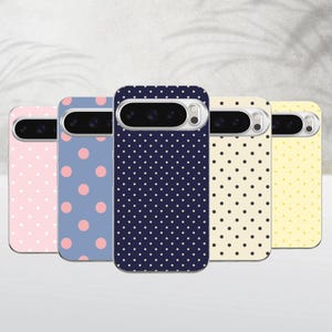 Può includere: Cinque cover per smartphone disposte in fila, ognuna con un motivo a pois distinto. I colori includono rosa chiaro, blu, blu navy scuro, crema e giallo. Ogni cover presenta un'apertura orizzontale per la fotocamera con un bordo argentato.