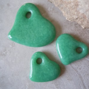 May include: Three green heart-shaped pendants with holes for stringing. The pendants are made of a smooth, polished material.