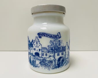 Tarro vintage de vidrio blanco para guardar mostaza con diseño azul histórico y tapa metálica giratoria. Decoración de cocina original.