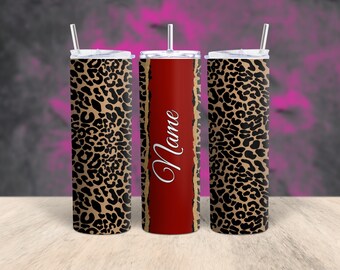 May include: A set of three stainless steel tumblers with lids and straws. The tumblers feature a leopard print design with a red center panel. The word "Name" is written in white script on the red panel. The tumblers are designed for cold beverages.