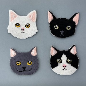 May include: Four embroidered cat face patches. Two are black and white, one is gray, and one is white.