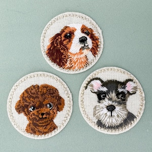 Pode incluir: Três patches bordados com diferentes raças de cães. Os patches são circulares e têm um fundo branco com uma borda bege. O primeiro patch apresenta um Cavalier King Charles Spaniel com pelo castanho e branco. O segundo patch apresenta um Poodle com pelo castanho. O terceiro patch apresenta um Schnauzer miniatura com pelo cinzento e preto.