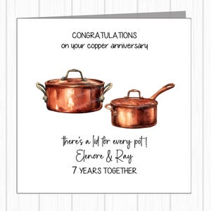May include: A white card with the text "CONGRATULATIONS on your copper anniversary." It features illustrations of two copper pans and the text "there's a lid for every pot! Elenore & Ray 7 YEARS TOGETHER."