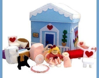 Könnte beinhalten: Ein Filz-Spielhaus mit blauer Außenwand, weißen Verzierungen und einem roten Herzen an der Tür. Das Haus ist umgeben von Filzmöbeln und Spielzeug, darunter ein Kinderwagen, ein Bettchen, ein Stuhl und eine Puppe. Das Haus hat die Nummer "123" an der Seite.