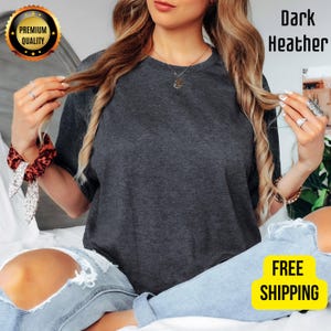 K&ouml;nnte beinhalten: Dunkelgraues meliertes T-Shirt mit Rundhalsausschnitt. Das Shirt ist einfarbig und hat eine lockere Passform. Das Bild enth&auml;lt auch ein gold-schwarzes "Premium Quality"-Abzeichen und ein gelbes "FREE SHIPPING"-Abzeichen.