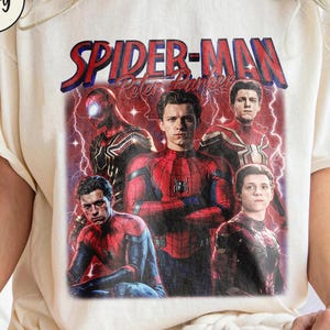 K&ouml;nnte beinhalten: Cremefarbenes T-Shirt mit einem Spider-Man-Motiv und dem Text "SPIDER-MAN Peter Parker" in Rot und Blau. Das Design zeigt mehrere Bilder von Spider-Man in verschiedenen Posen vor einem roten und violetten Hintergrund.