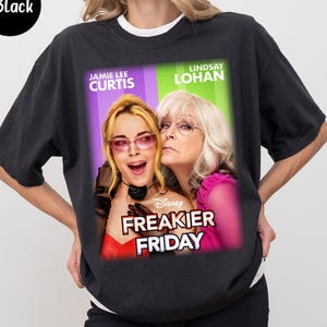 May include: Black graphic t-shirt featuring the movie poster for "Freakier Friday" with Jamie Lee Curtis and Lindsay Lohan. The Disney movie title is in white, with the actors' names above their images. The shirt is a dark colour.