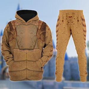 May include: A two-piece outfit comprising a hooded sweatshirt and matching sweatpants. The set is in tan and brown, with an armour-like design. The hoodie has a black hood lining. The sweatpants feature a speckled pattern.