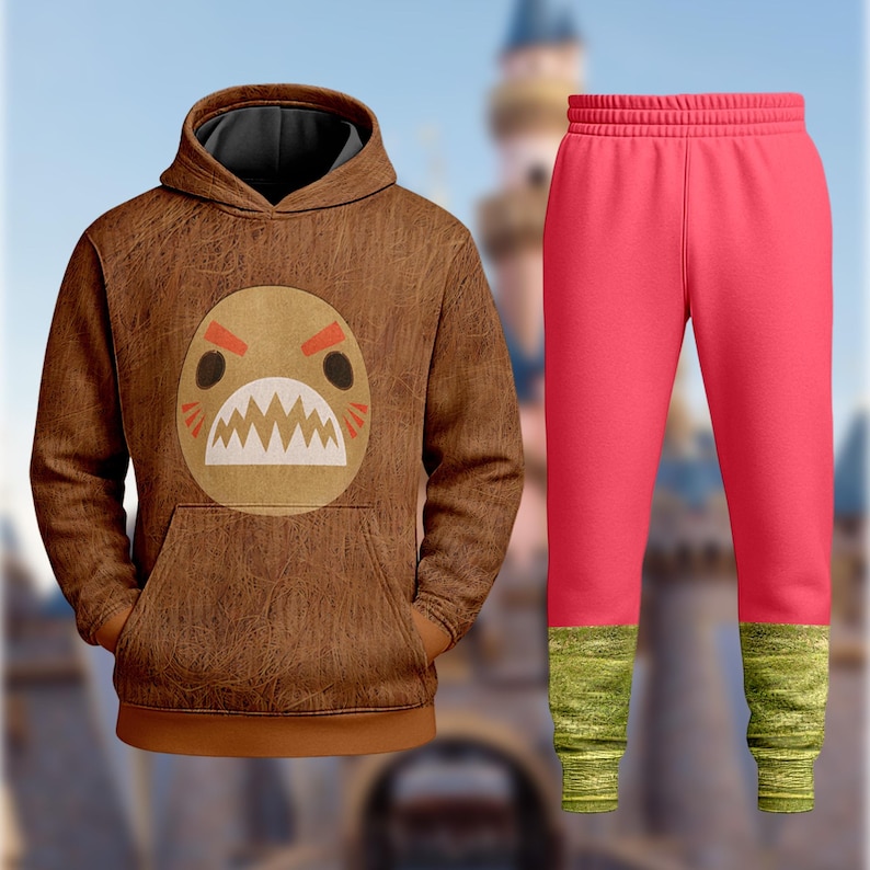 A brown hoodie with a cartoon monster design and a pair of bright pink pants are displayed against a blurred background.