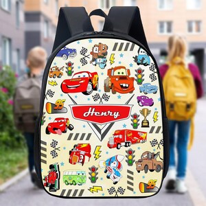May include: A yellow and black Cars-themed backpack with a red name tag that says "Henry". The backpack features a variety of Cars characters, including Lightning McQueen, Mater, and Tow Mater.