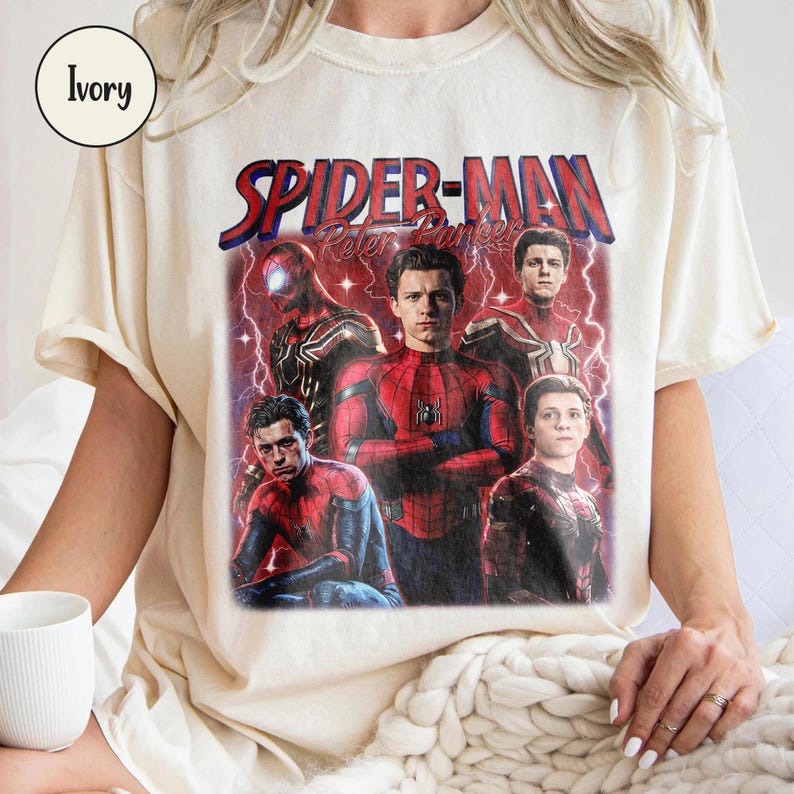 K&ouml;nnte beinhalten: Cremefarbenes T-Shirt mit einem Spider-Man-Motiv und dem Text "SPIDER-MAN Peter Parker" in Rot und Blau. Das Design zeigt mehrere Bilder von Spider-Man in verschiedenen Posen vor einem roten und violetten Hintergrund.