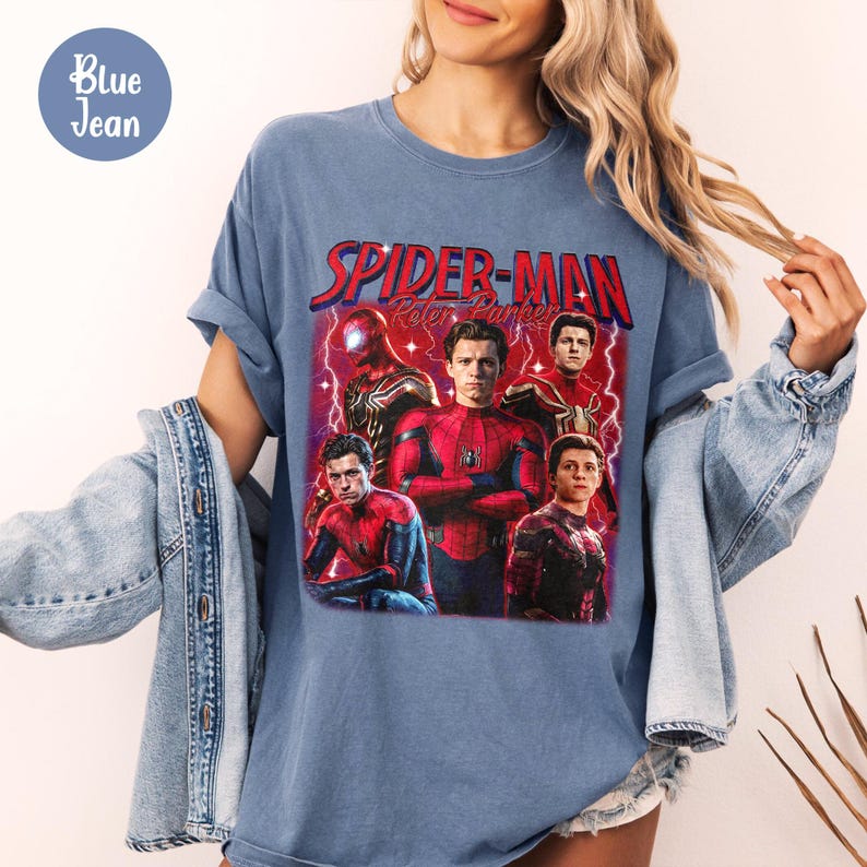 K&ouml;nnte beinhalten: Blaues T-Shirt mit einem Spider-Man-Motiv und dem Text "Spider-Man Peter Parker" in Rot. Das Design zeigt mehrere Bilder von Spider-Man. Das T-Shirt hat einen Vintage-Look.