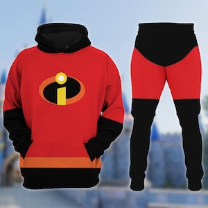 May include: Red hoodie and black pants set featuring the Incredibles logo. The hoodie has a black hood and sleeves, with an orange stripe across the midsection. The pants are red with black sections at the waist and lower legs. The set is designed to resemble the superhero family's costumes.