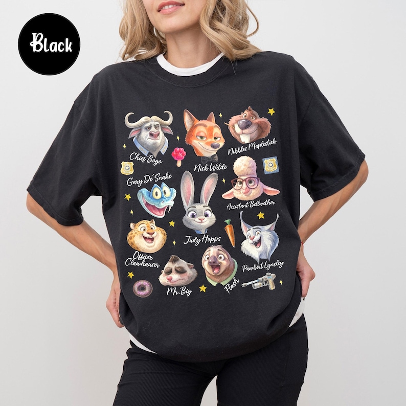 May include: Black graphic t-shirt featuring cartoon characters from Zootopia, including Chief Bogo, Nick Wilde, and Judy Hopps. The shirt has a crew neck and short sleeves. The word "Black" is in a black circle in the upper left corner.
