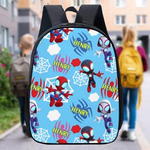 May include: A black backpack with a light blue front panel featuring cartoon Spider-Man characters, spiderwebs, and the name "HENRY" in red and white. The backpack has a top handle and adjustable shoulder straps, suitable for carrying school supplies.