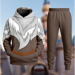A hooded sweatshirt with a graphic design and a pair of brown sweatpants are displayed against a blurred background.
