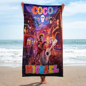May include: A colorful beach towel featuring characters from the Disney Pixar movie Coco. The towel has the word "Coco" in large, colorful letters at the top and the name "Michael" in colorful letters at the bottom. The towel features a scene from the movie with the characters Miguel, Hector, and Dante.