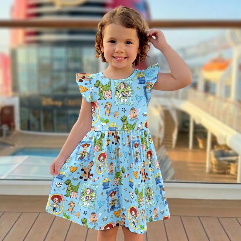 Puede incluir: Un vestido azul claro con un estampado de Toy Story. El vestido tiene cuello redondo, mangas con volantes y un corpi&ntilde;o ajustado que fluye hacia una falda acampanada. El estampado incluye personajes como Buzz Lightyear, Woody y Rex. El vestido lo lleva una ni&ntilde;a.
