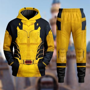 Peut inclure: Un ensemble composé d'un sweat à capuche et d'un pantalon de jogging jaune et noir, arborant un motif imprimé imitant un blindage, avec une ceinture graphique ornée d'un emblème en X rouge sur le sweat et des détails de genouillères.