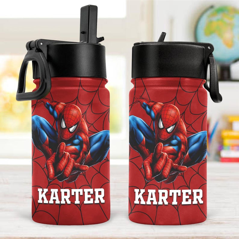 May include: Two red water bottles featuring a graphic of the character Spider-Man in a crouching pose against a black spiderweb pattern. Each bottle has a black lid with a flip-up straw and a carry loop. The name KARTER is printed in white.