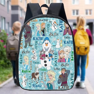 May include: A black backpack featuring characters from the movie "Frozen" on a light blue background. The backpack has images of Olaf, Elsa, Anna, and Kristoff, with the name "Katie" repeated throughout the design.