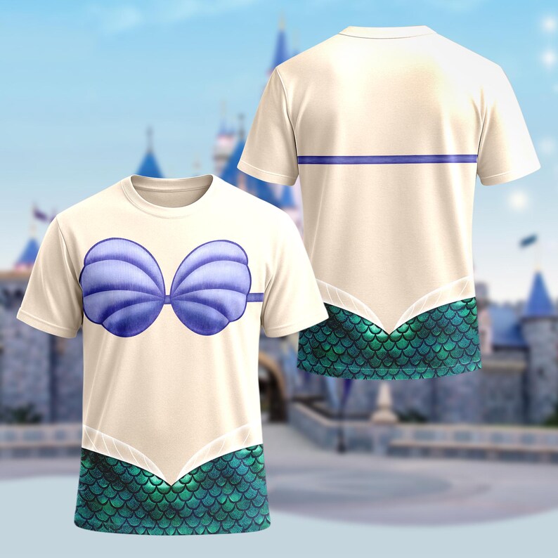 Op de afbeelding: Een cr&egrave;mekleurig T-shirt met een blauw schelpenbh-ontwerp op de voorkant. De onderkant van de shirt heeft een groen en blauw schubbenpatroon, met een bijpassend ontwerp op de achterkant. De shirt is een leuk, grillig ontwerp.