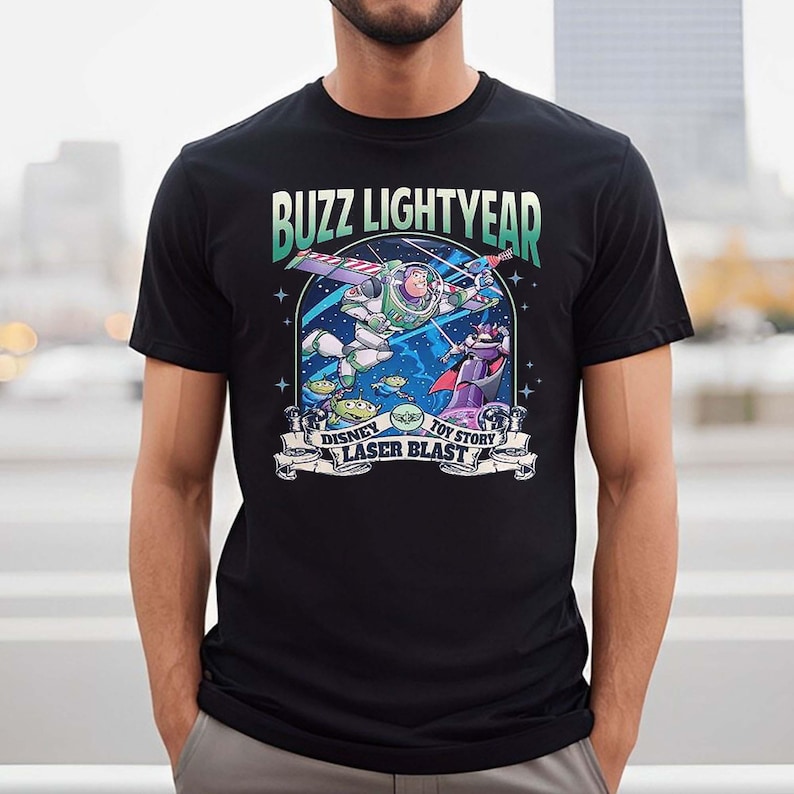 Puede incluir: Una camiseta negra con un gr&aacute;fico de Buzz Lightyear de Toy Story. El gr&aacute;fico presenta a Buzz en el espacio con una explosi&oacute;n de l&aacute;ser y el texto "Buzz Lightyear", "Disney", "Toy Story" y "Laser Blast".