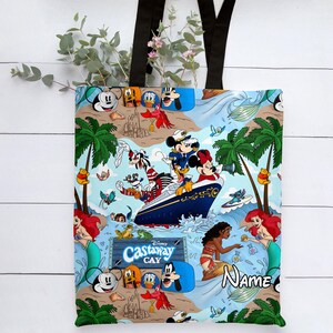 May include: A blue and white tote bag with a Disney Castaway Cay theme. The bag features Mickey Mouse, Minnie Mouse, Goofy, Donald Duck, and other Disney characters. The bag also features a ship, palm trees, and the words "Disney Castaway Cay".