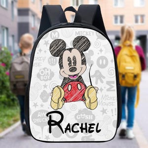May include: Black backpack with a large Mickey Mouse graphic and the name "Rachel" in black script. The white background has grey Mickey Mouse-themed doodles. The straps and back of the backpack are black.