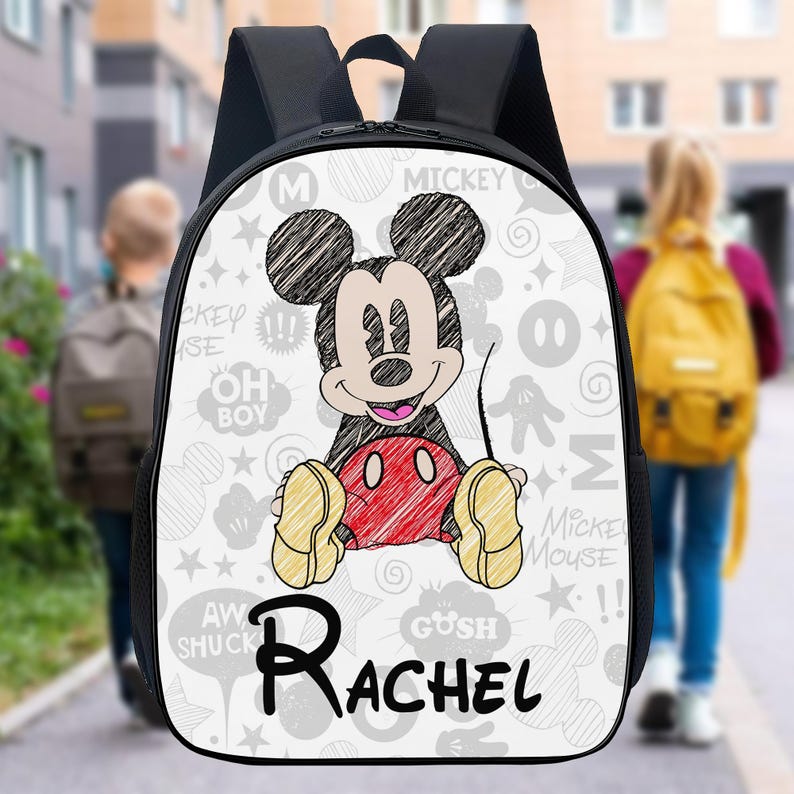 May include: Black backpack with a large Mickey Mouse graphic and the name "Rachel" in black script. The white background has grey Mickey Mouse-themed doodles. The straps and back of the backpack are black.