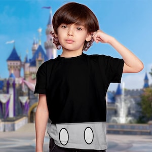 May include: A black short-sleeved t-shirt featuring a light grey horizontal band across the bottom hem. The grey section displays two vertically oriented white oval shapes with thin black outlines, mimicking the iconic design of cartoon shorts.