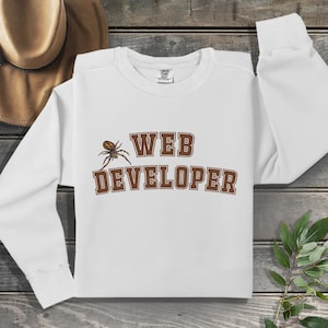 May include: White long-sleeved sweatshirt with brown text that reads "WEB DEVELOPER" and a brown spider graphic.