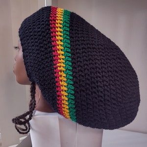 Peut inclure: Béret noir en crochet avec une bande rouge, jaune et verte. Le béret est porté sur une tête de mannequin.