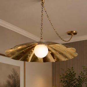 May include: A brass-colored, shell-shaped pendant light fixture with a white globe light in the center. The fixture hangs from a chain attached to the ceiling. The design is elegant and decorative.