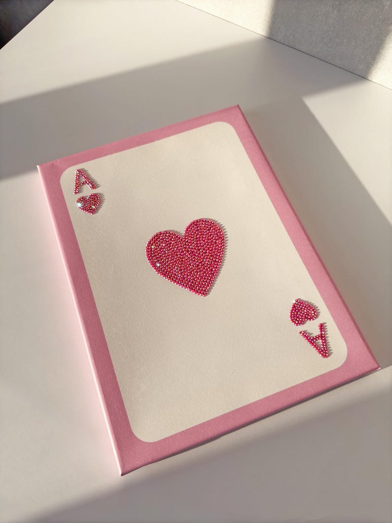 Peut inclure: Une peinture sur toile rose repr&eacute;sentant l'As de Coeur. La carte est faite de strass roses et a une bordure rose.