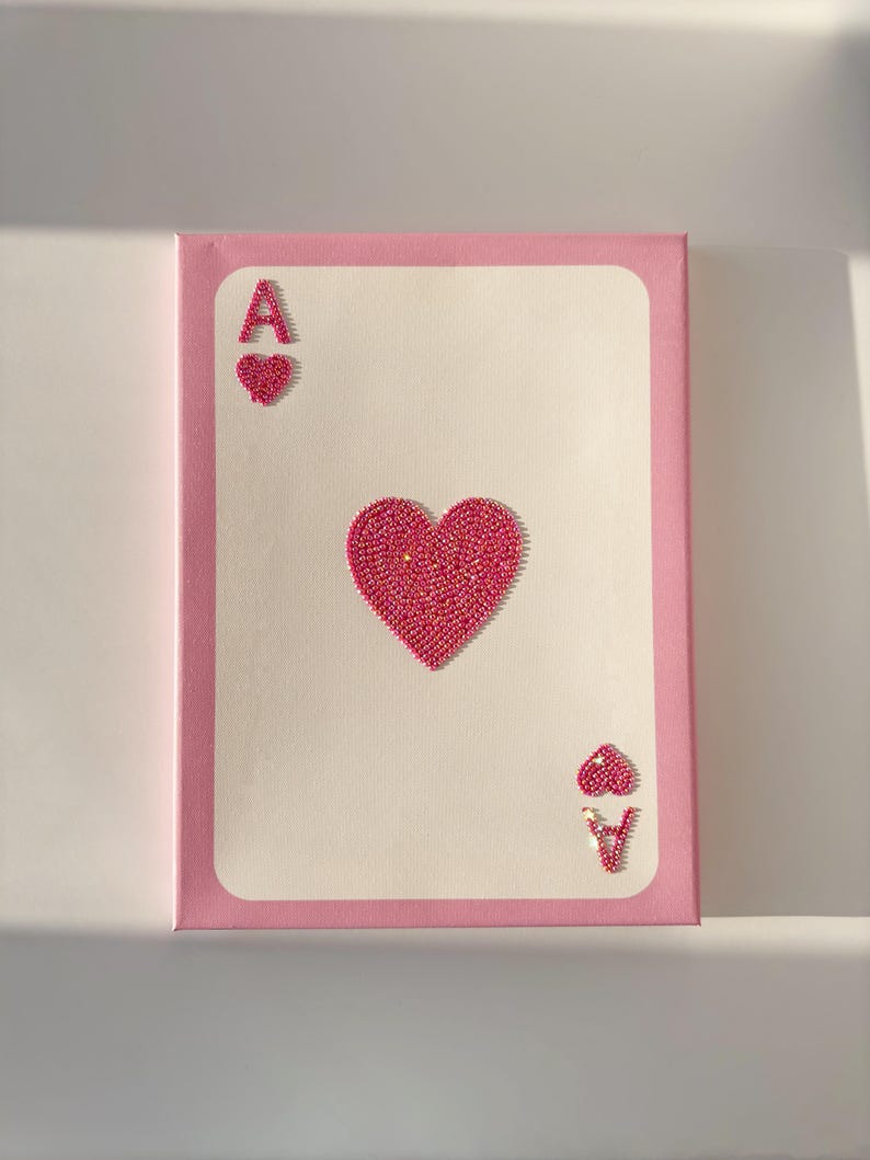 Peut inclure: Une peinture sur toile rose repr&eacute;sentant l'As de Coeur. La carte est faite de strass roses et a une bordure rose.