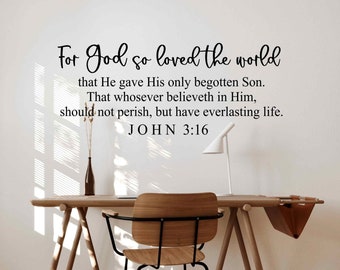 May include: A white wall with black text that reads "For God so loved the world that He gave His only begotten Son. That whosoever believeth in Him, should not perish, but have everlasting life. JOHN 3:16". A wooden desk with a chair and a brown leather folder are in the foreground.