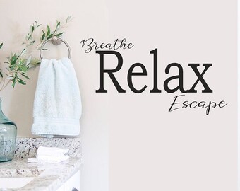 May include: White bathroom wall with a black vinyl decal that reads "Breathe Relax Escape".