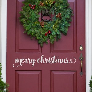 May include: A red front door with a green Christmas wreath and the words "merry christmas" written in white on the door.