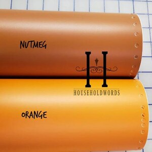 May include: Two rolls of vinyl material, one in a nutmeg brown and the other in a bright orange. The nutmeg roll has the word "NUTMEG" written on it, and the orange roll has the word "ORANGE" written on it. The logo "HOUSEHOLDWORDS" is also visible.