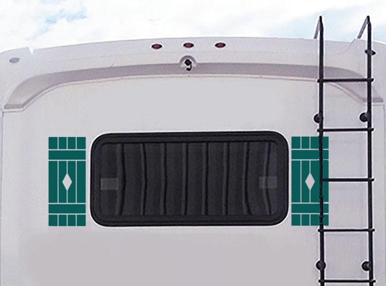 May include: A white camper van with a black ladder on the side. The van has two teal-colored window decals with a diamond shape in the center.