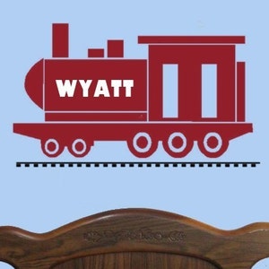 May include: Red train engine with the name Wyatt on the side. The train has four wheels and is on a track.