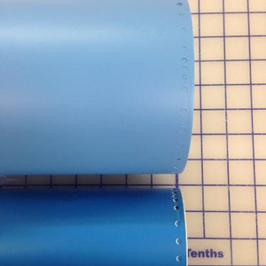 May include: Two blue tubes with a row of holes along the edge. The tubes are on a white grid background with a ruler at the bottom.