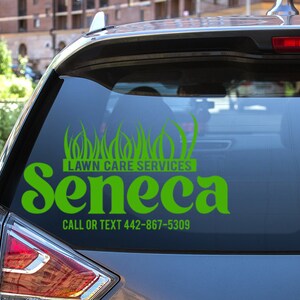 May include: A green vinyl decal on a car window advertising "Lawn Care Services" with the name "Seneca" in a stylized font. The decal includes a graphic of grass and a phone number.