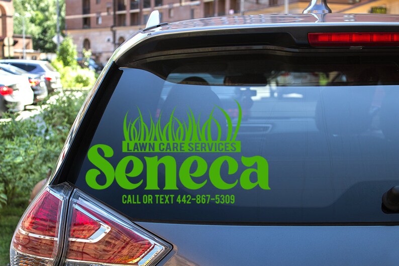 May include: A green vinyl decal on a car window advertising "Lawn Care Services" with the name "Seneca" in a stylized font. The decal includes a graphic of grass and a phone number.