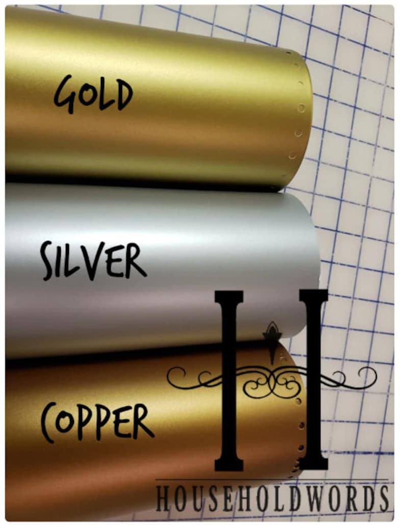 May include: Three rolls of metallic vinyl in gold, silver, and copper. The word "GOLD" is written in black on the gold roll, "SILVER" on the silver roll, and "COPPER" on the copper roll. The image also includes the text "HOUSEHOLDWORDS".