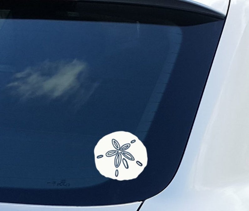 May include: A white car with a white sand dollar sticker on the back window.